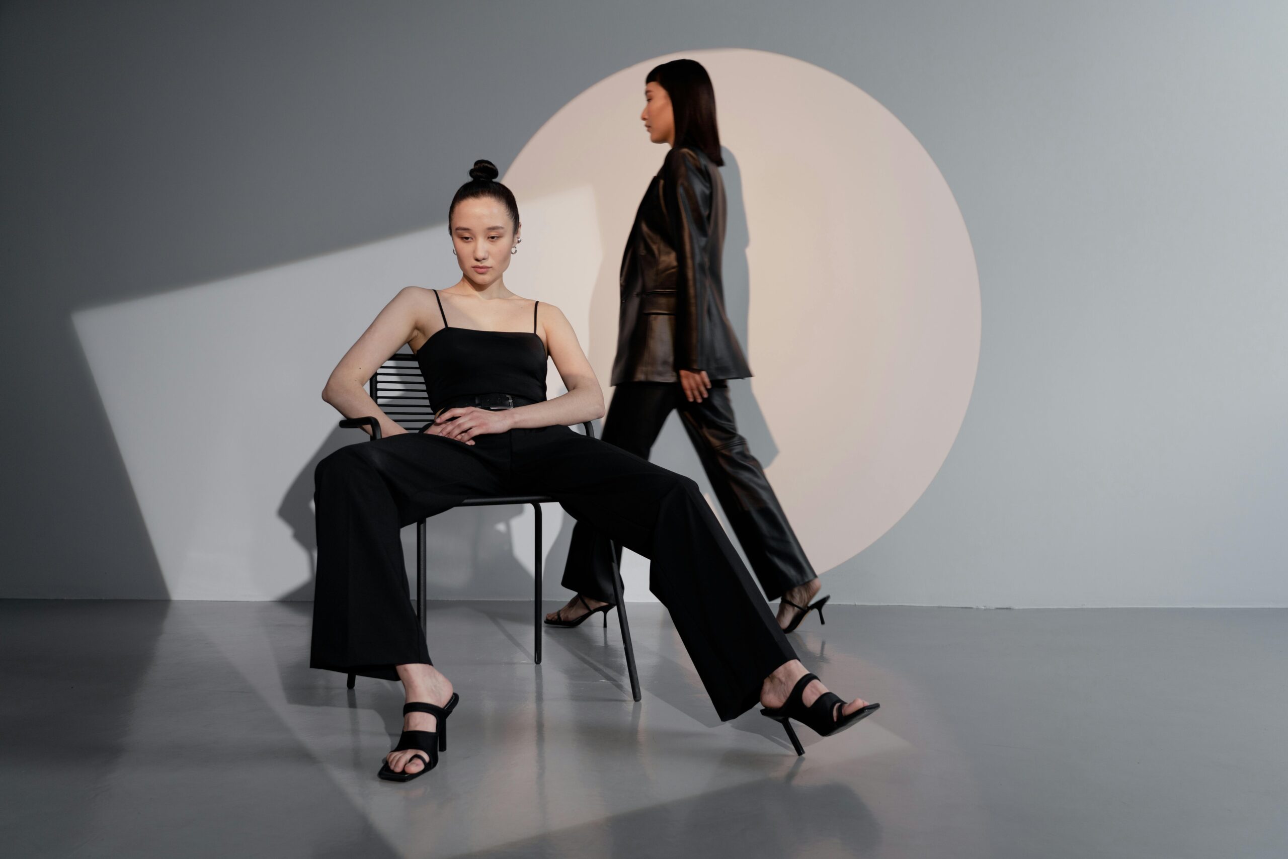 Stylish models posing in a modern studio setting with dramatic lighting and sleek fashion.